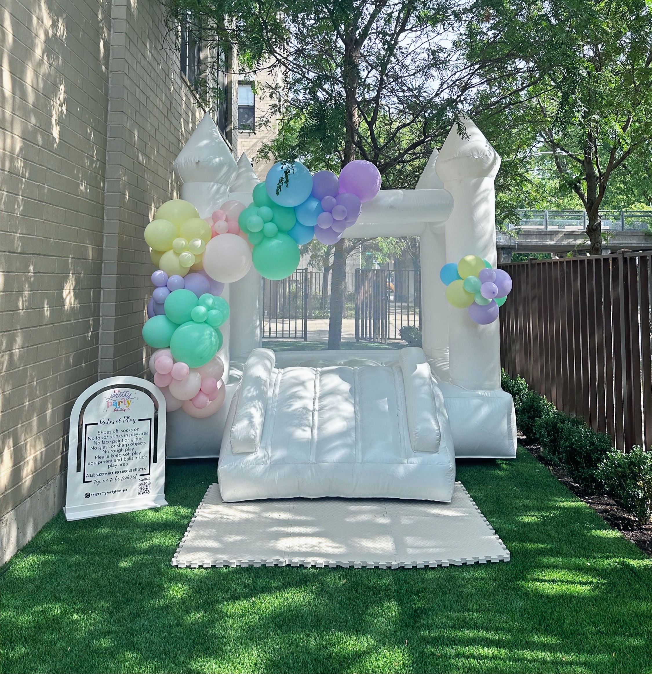 White castle bounce house with pastel balloon decoration