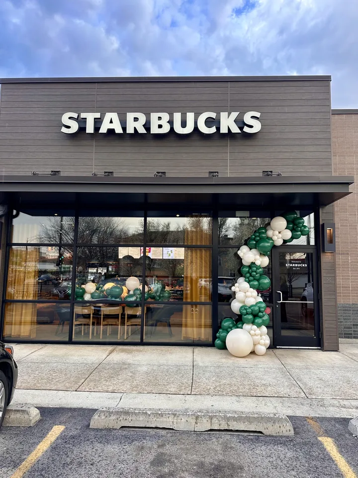 Green and cream balloon garland framing the entrance to a Starbucks storefront. corporate balloon decor design inspiration for Des Plaines; photographed location unverified.