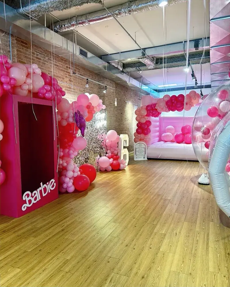 Pink balloon clusters around a reflective wall, a marquee 6 and pink party rentals