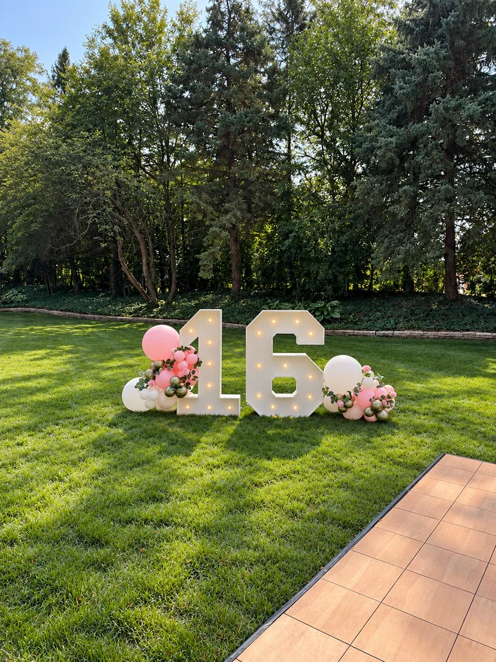 Illuminated 16 marquee numbers with pink, white and gold balloons outdoors