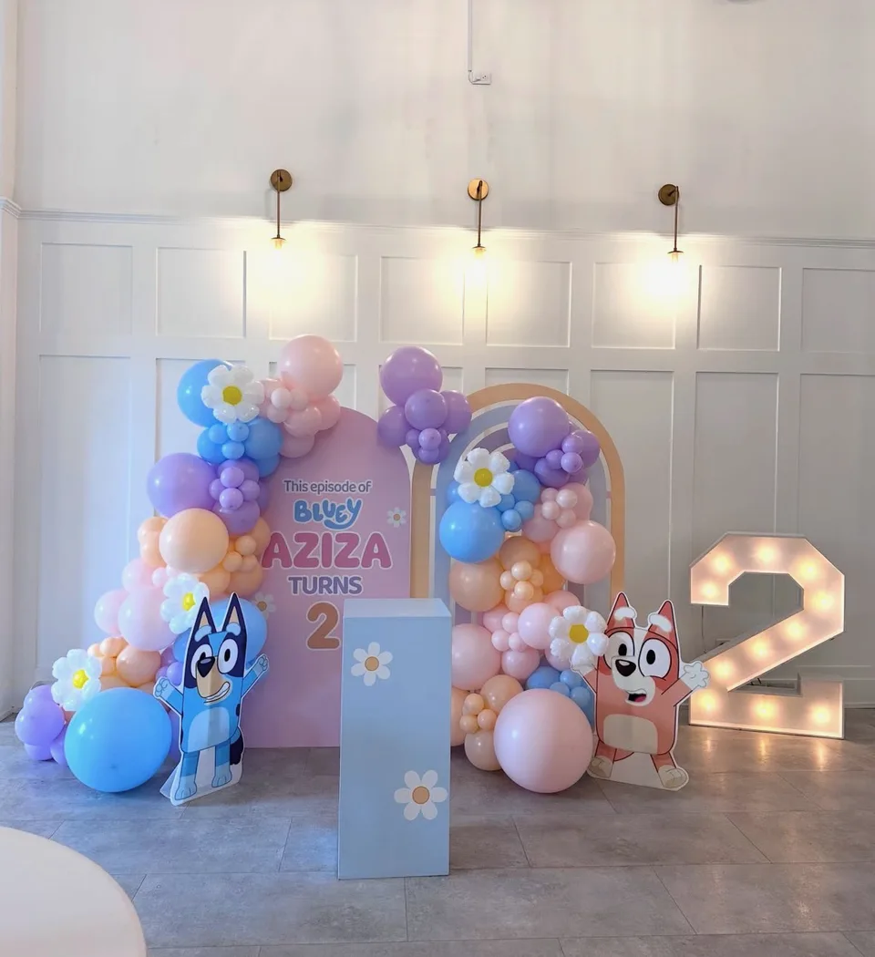 Pastel balloon clusters around cartoon birthday panels and an illuminated number two