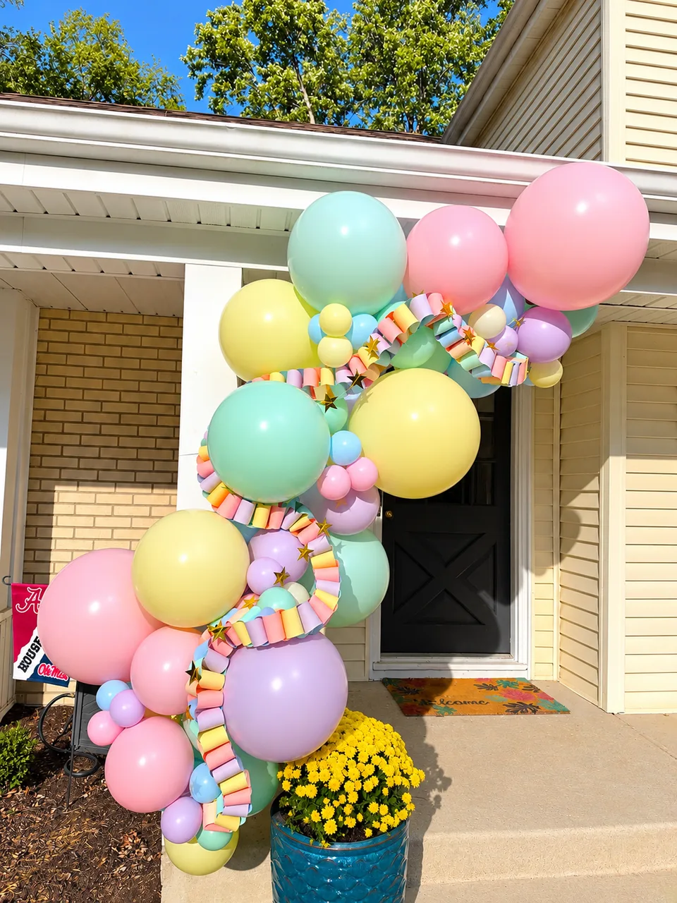 Pastel pink, mint, yellow and lilac balloons with patterned accents beside a front door