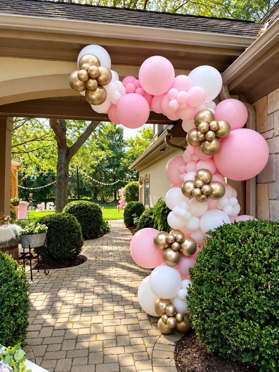 Pink, white and metallic gold balloon garland framing a covered outdoor walkway