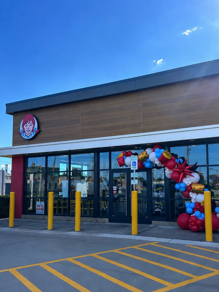 Red, blue, yellow and white balloon garland at the entrance to a Wendy's restaurant. corporate balloon decor design inspiration for Wheaton; photographed location unverified.